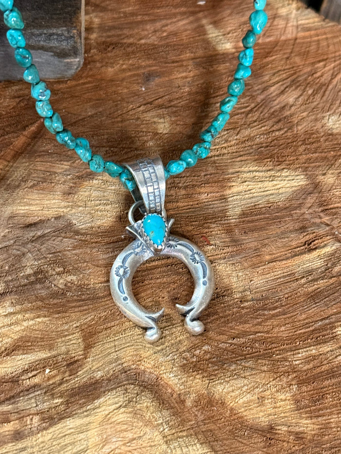 Turquoise bead necklace with silver Naja pendant detail and blue center stone.