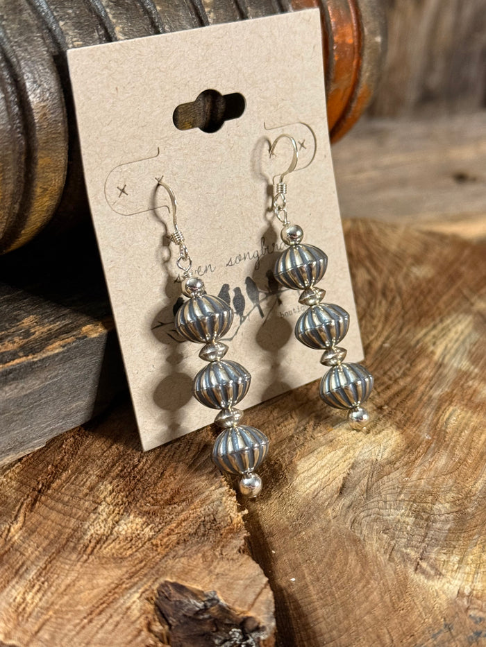 Silver-tone pumpkin bead fishhook earrings with three dangling tiers, side view