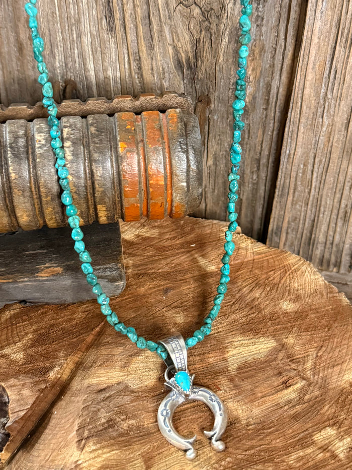 Turquoise bead necklace with silver Naja pendant and circular bead accent.