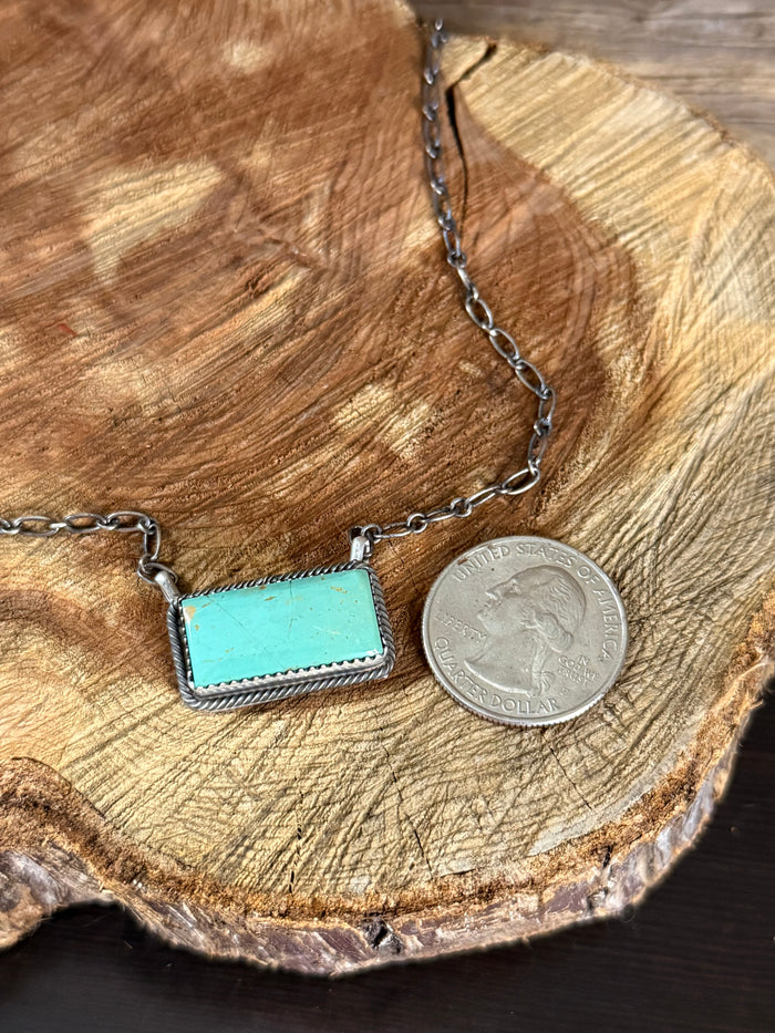Silver chain necklace with turquoise rectangle pendant and silver coin for scale