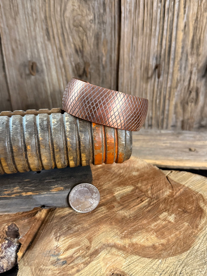Copper cuff bracelet with diamond-hammered texture, shown next to a coin