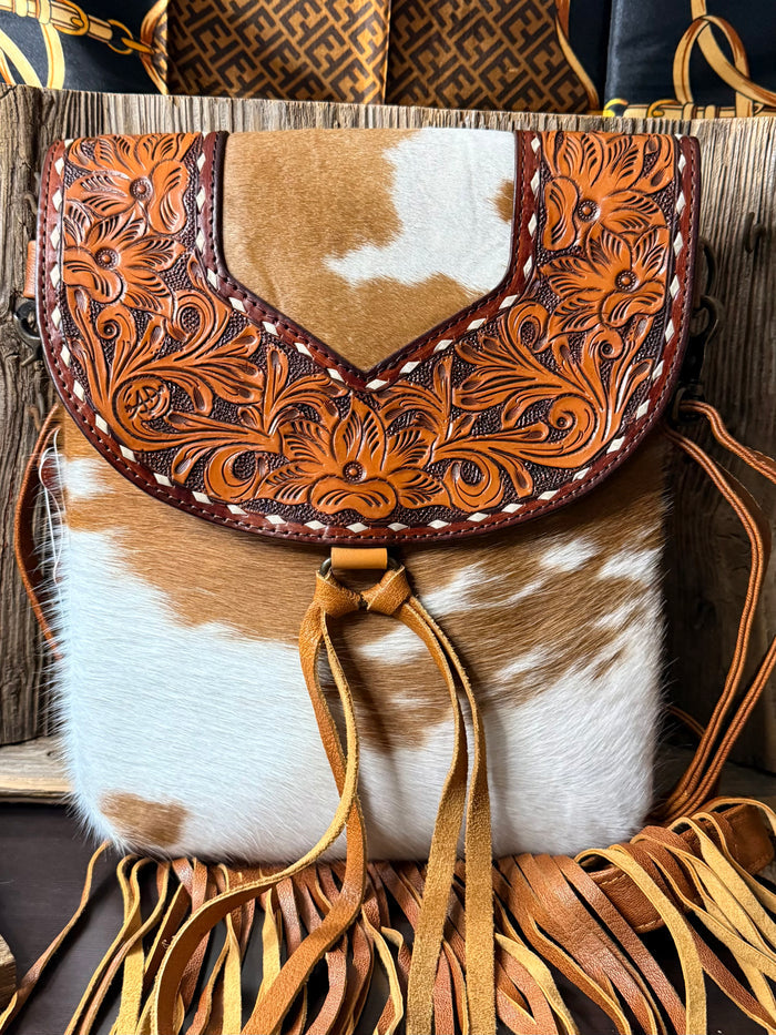 Cowhide crossbody purse with tooled leather overlay and long tan fringe tassels