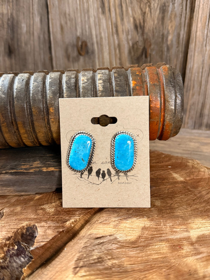 Turquoise oval stud earrings with silver rope bezel on display card