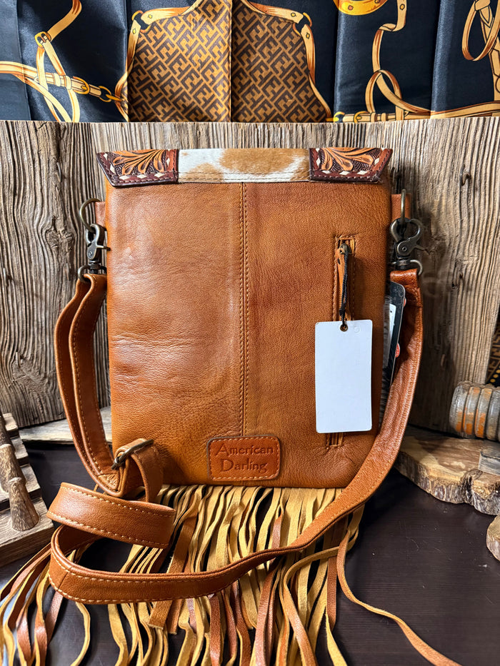 Brown leather crossbody purse with adjustable strap, dangling tag, and fringe