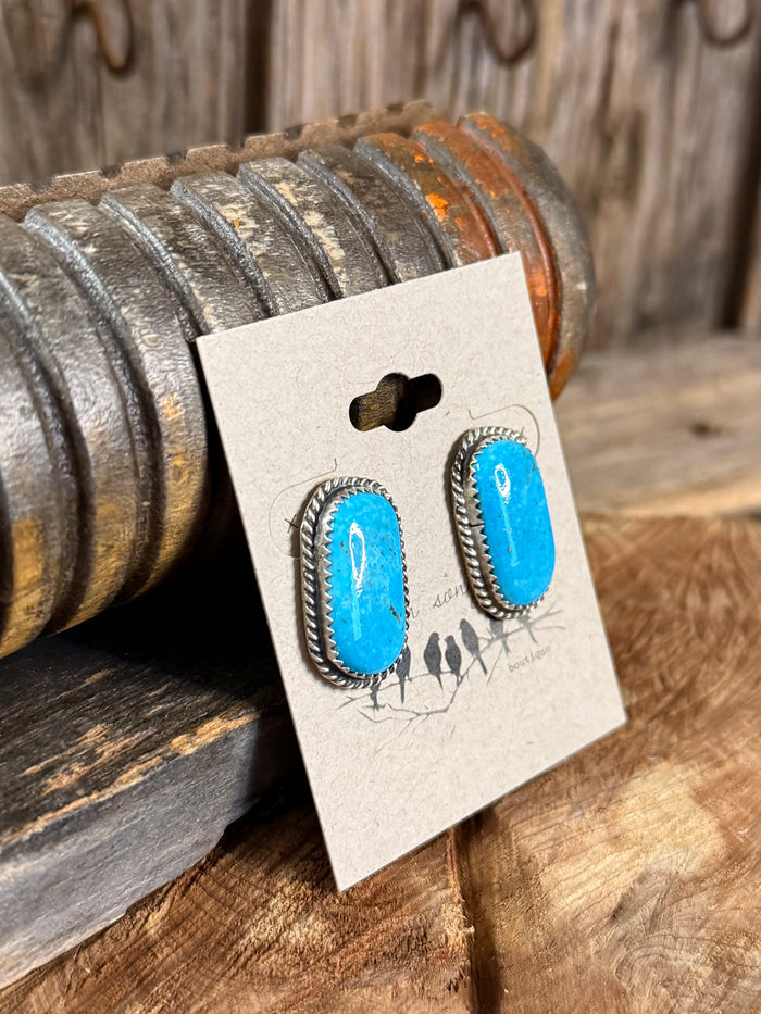 Turquoise oval stud earrings with silver rope edging on hanging card