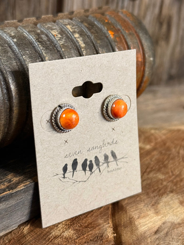 Pair of orange spiny oyster stud earrings with textured silver-tone bezel, close-up on card