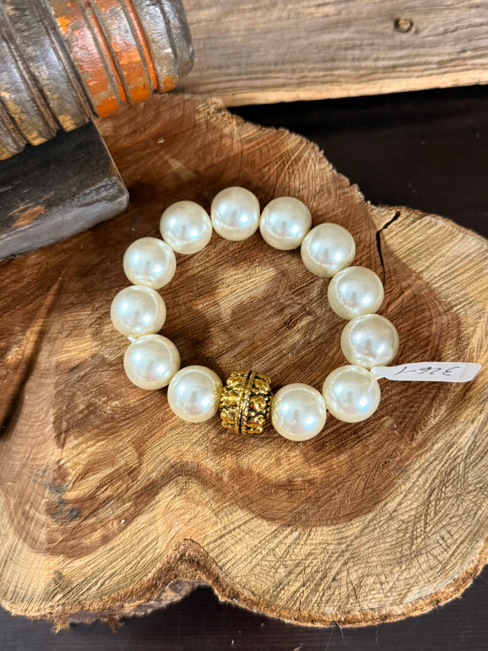 Pearl stretch bracelet featuring round pearls and a gold decorative center medallion