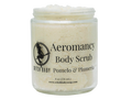 A clear glass jar of Witch Baby Aeromancy Body Scrub with a white lid, filled with a pale cream-colored scrub. The front label features black text and a witch silhouette logo.