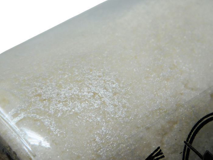 A close-up of a translucent, frosted glass or acrylic surface with a milky white texture and a small portion of a black circular object visible in the lower right corner.