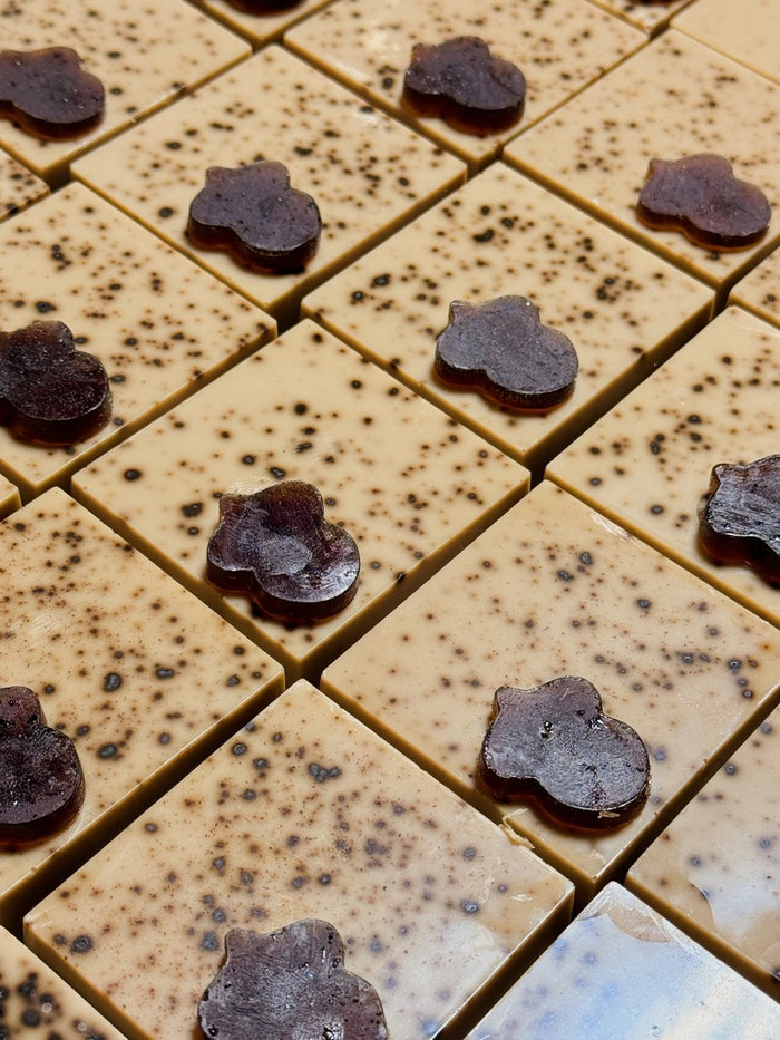 Close-up of square coffee colored dark brown speckles and glossy dark brown acorn-shaped accents, arranged in a grid.
