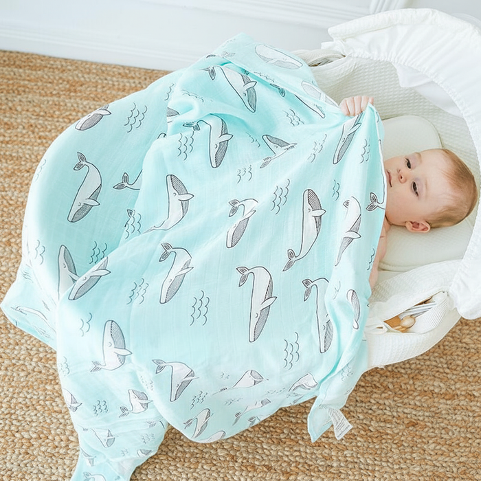 Baby wrapped in bamboo cotton swaddle blanket on a natural jute rug