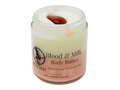 4 oz glass jar containing two color body butter. Top is white and bottom is pink. Topped with red jasper. Label says blood and milk body butter, blood orange and coconut milk.