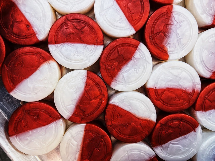 A close-up, top-down view of multiple round soaps with a red and white diagonal split design, arranged tightly together.