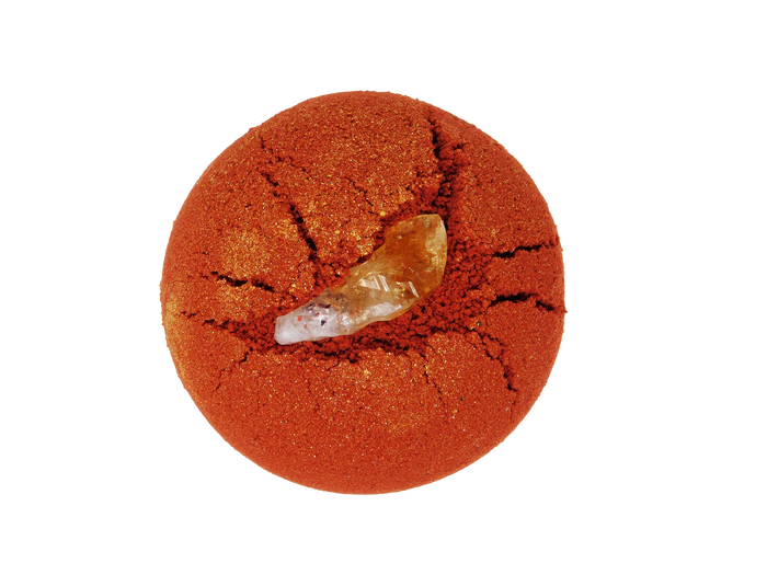 circular red bath bomb witih citrine pressed into it. Topped with gold glitter.