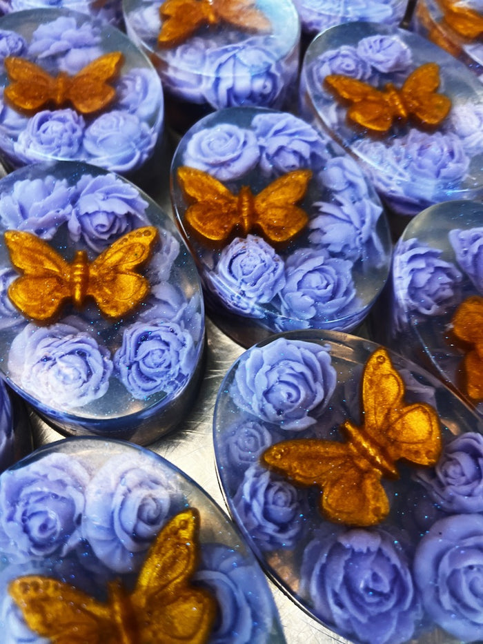 A close-up of soaps lavender-blue roses and a small gold butterfly