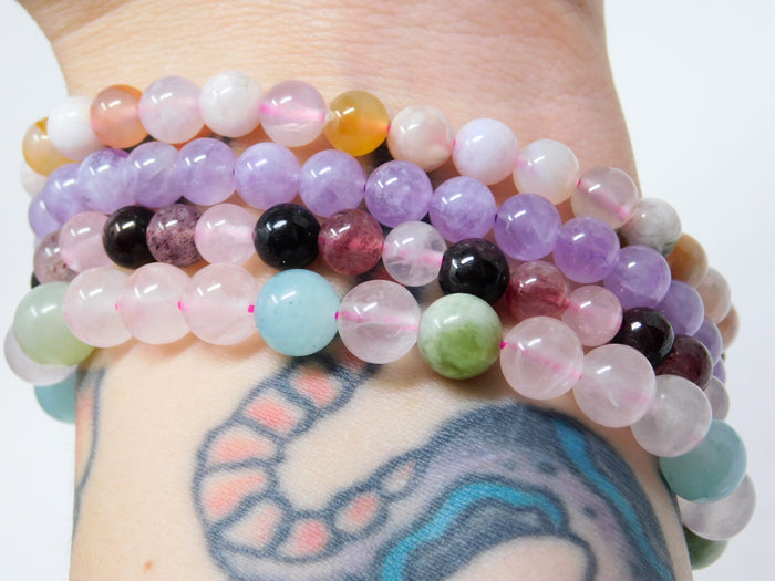 Colorful beaded bracelets on a wrist with a tattoo in the background