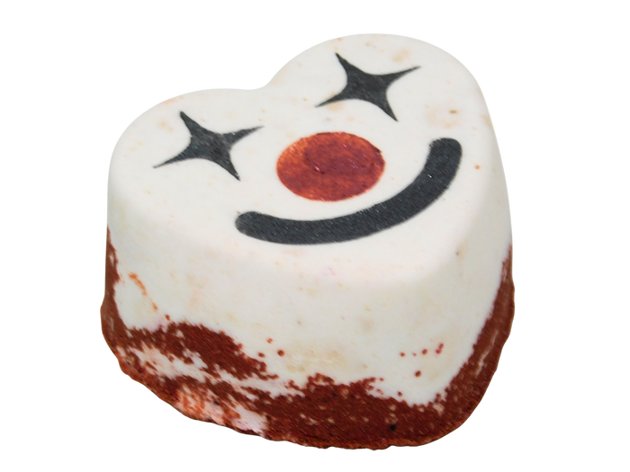 A heart-shaped  white and red bath bomb decorated with a black smiley clown face, isolated on a white background.