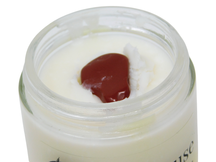 An open clear glass jar of Fun House containing a white cream or balm, with a tumbled red jasper crystal on top, photographed against a plain white background.
