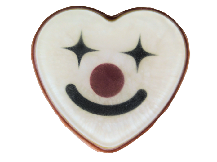 A heart-shaped white soapwith a black smiley clown face, star eyes, and a red nose, isolated on a white background.