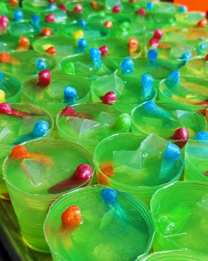A close-up view of many small green translucent cup shaped soaps fashioned to look like lime green gummy worm magaritas