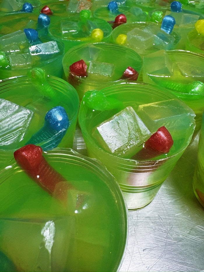 A close-up view of many small green translucent cup shaped soaps fashioned to look like lime green gummy worm magaritas
