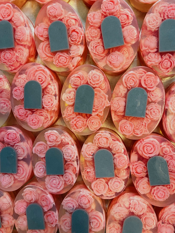 A close-up, top-down view of multiple ovalsoaps filled with pink rose-shaped elements and a gray tombstone accent, arranged in a repeating pattern.