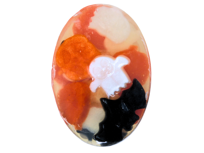 Oval-shaped soap with orange, white, and black halloween shapes on a white background