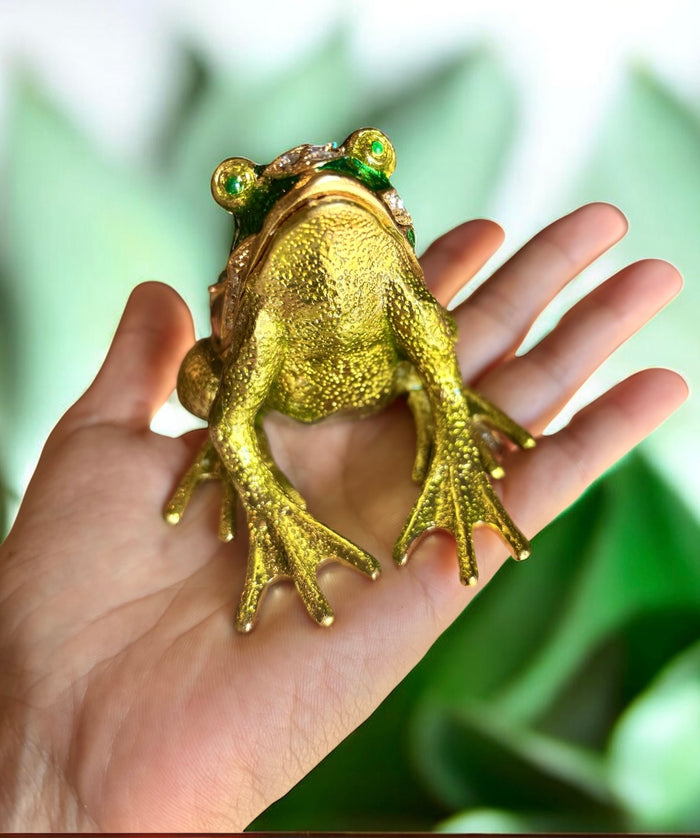 Hand held gold tone green enamel frog trinket box with rhinestones, front view showing textured frog body against green leaf background