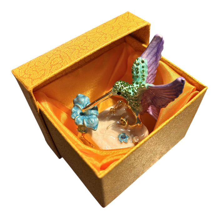 Jeweled hummingbird trinket box open showing warm amber interior and magnetic closure, white background