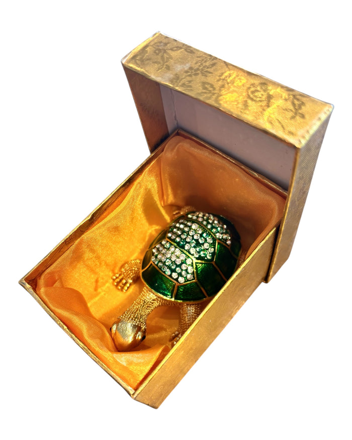 Jeweled tortoise trinket box nestled inside open gold brocade gift box with golden orange satin lining, white background