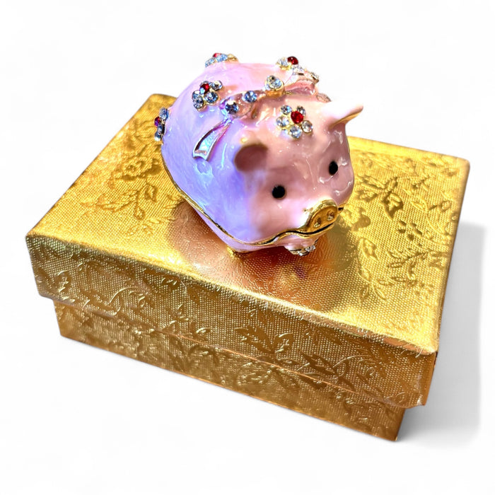Pink enamel jeweled pig trinket box, three-quarter side view showing rhinestone flower clusters and gold trim on white background