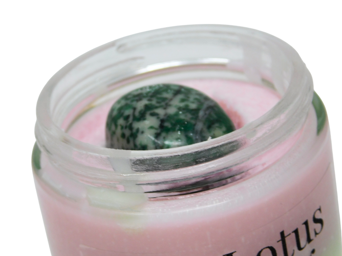 Jar of pink cream with a green stone inside on a white background