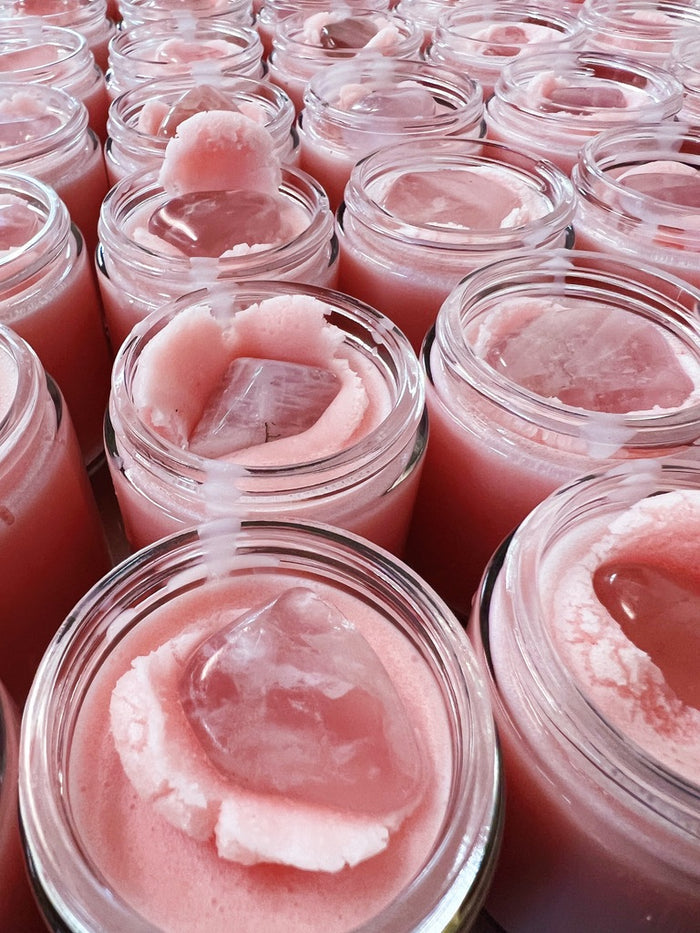 pink body butters in glass jars topped with rose quartz crystals
