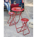 Old Glory patriotic folding metal table and two stool set featuring bold red, white, and blue stars and stripes design, shown collapsed flat for compact storage at 4 inches deep, lightweight and portable for tailgating, camping, and Fourth of July outdoor gatherings