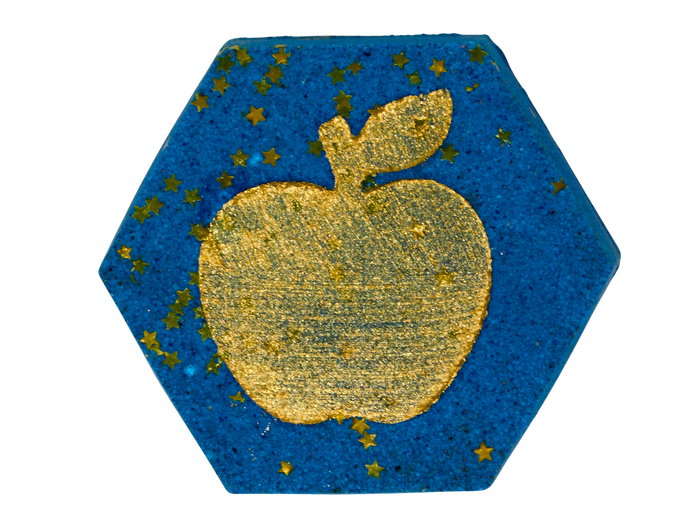 A hexagonal blue bath bomb featuring a large gold apple in the center, surrounded by small scattered gold stars, shown on a plain white background.