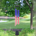 Patriotic USA American flag wind chime with 5 aluminum tubes in red, white, and blue stars and stripes, hanging outdoors in a lush green garden setting, 56 inches long