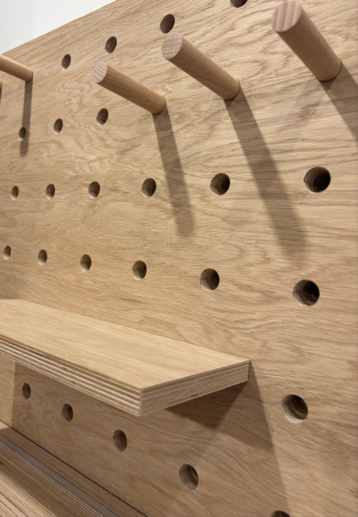 Close-up of a wooden oak veneer pegboard with pegs, showing the texture and details.