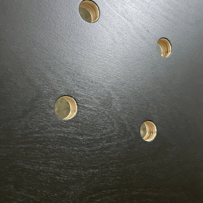 detail of black painted pegboard showing the wood grain