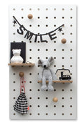 large white wooden pegboard with peg hooks and shelves in kids room