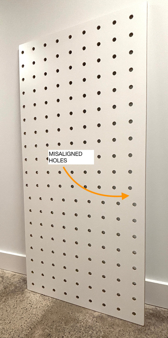Pegboard with misaligned holes labeled on a white wall.