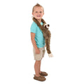 Smiling young boy with a plush hanging sloth draped over his shoulders like a scarf, the sloth's long shaggy brown arms wrapping around him, white background