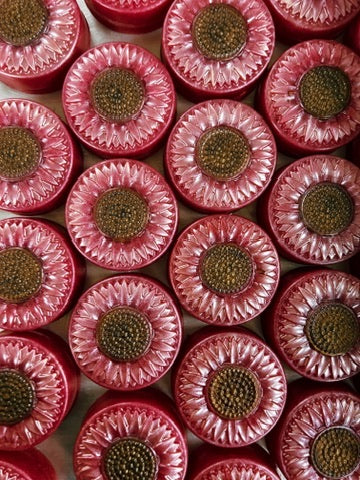 A close-up, top-down view of multiple round  pink sunflower soaps arranged in a grid.