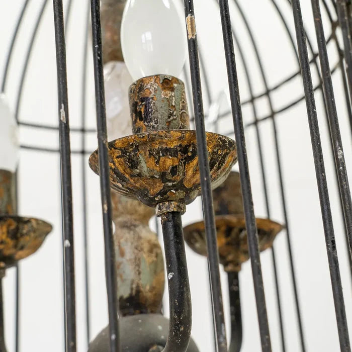 Rustic metal bird cage pendant lamp with distressed finish and candelabra bulb holders, hanging by chain close up