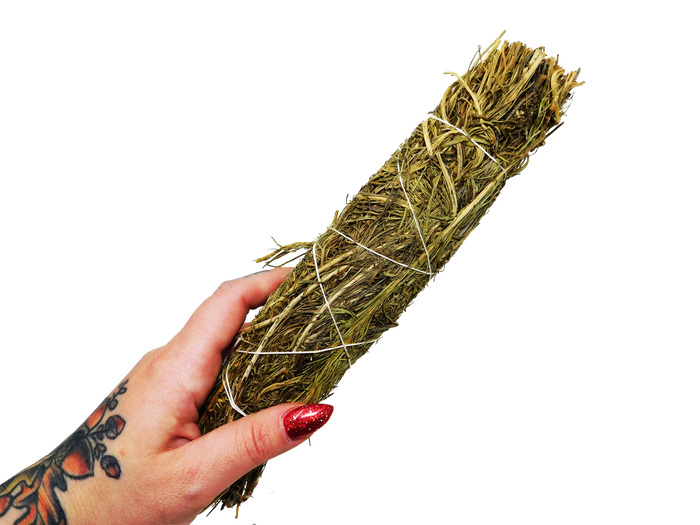 hand holding green sage leaves bundled with white string
