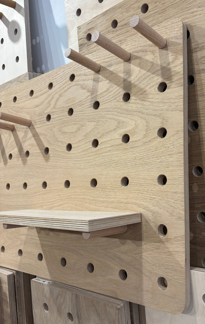 Wooden pegboard with holes and hooks on a light background