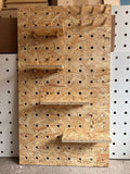 Pegboard with wooden pegs attached to a wall OSB with shelves
