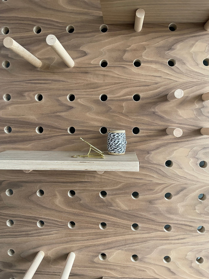 Walnut veneer birch plywood pegboard by kreisdesign with shelves and pegs that are fitted with pegs to slot into the pegboard holes