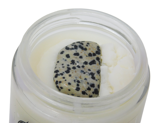 Close-up of a jar with a dalmation jasper crystal inside body butter
