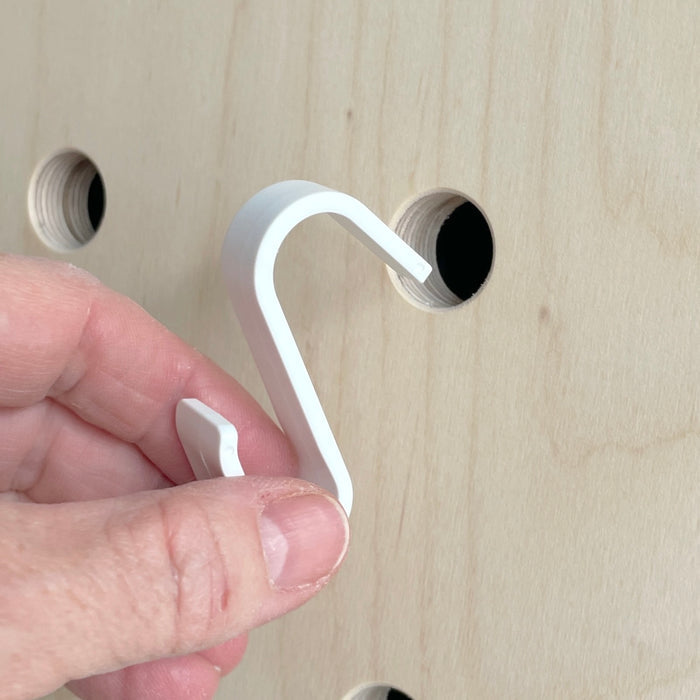Detail of white hook that fits into the pegboard to hang the basket